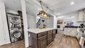 Une cuisine moderne dotée d’un îlot central, d’appareils électroménagers intégrés et d’un lustre.