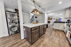 Een moderne keuken met een centraal eiland, inbouwapparatuur en een kroonluchter.