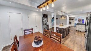 Une cuisine moderne avec des meubles blancs, un îlot central et un coin repas comprenant une table et des chaises en bois.