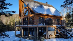 Eine Blockhütte mit einer großen Terrasse und einem Steinfundament.