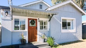 A single-story house with a wooden front door, a small porch, and a wreath above the door.