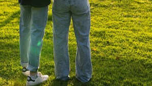 Dos personas de pie en un campo cubierto de hierba, con árboles al fondo.