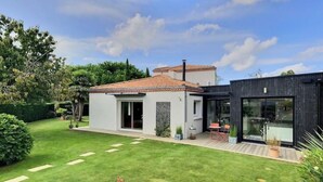 A modern house with a well-maintained lawn, a patio, and a large glass door leading to a deck.