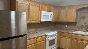 Una cocina con armarios de madera, un refrigerador de acero inoxidable, un microondas y un horno.