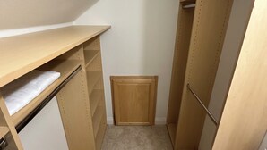 Un vestidor estrecho con estantes de madera y un pequeño armario de madera.