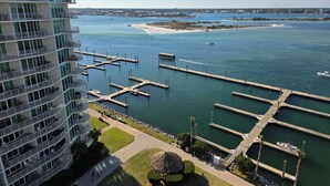 Een jachthaven met aangemeerde boten, een strand en een hoog hotel met balkons met uitzicht op het water.