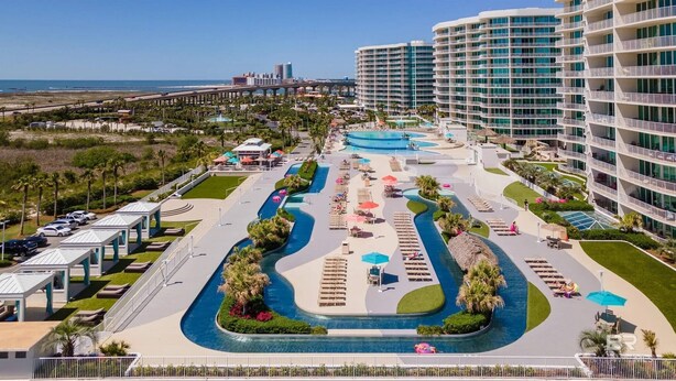 Een resort met meerdere zwembaden, een parkeerplaats en uitzicht op de oceaan.