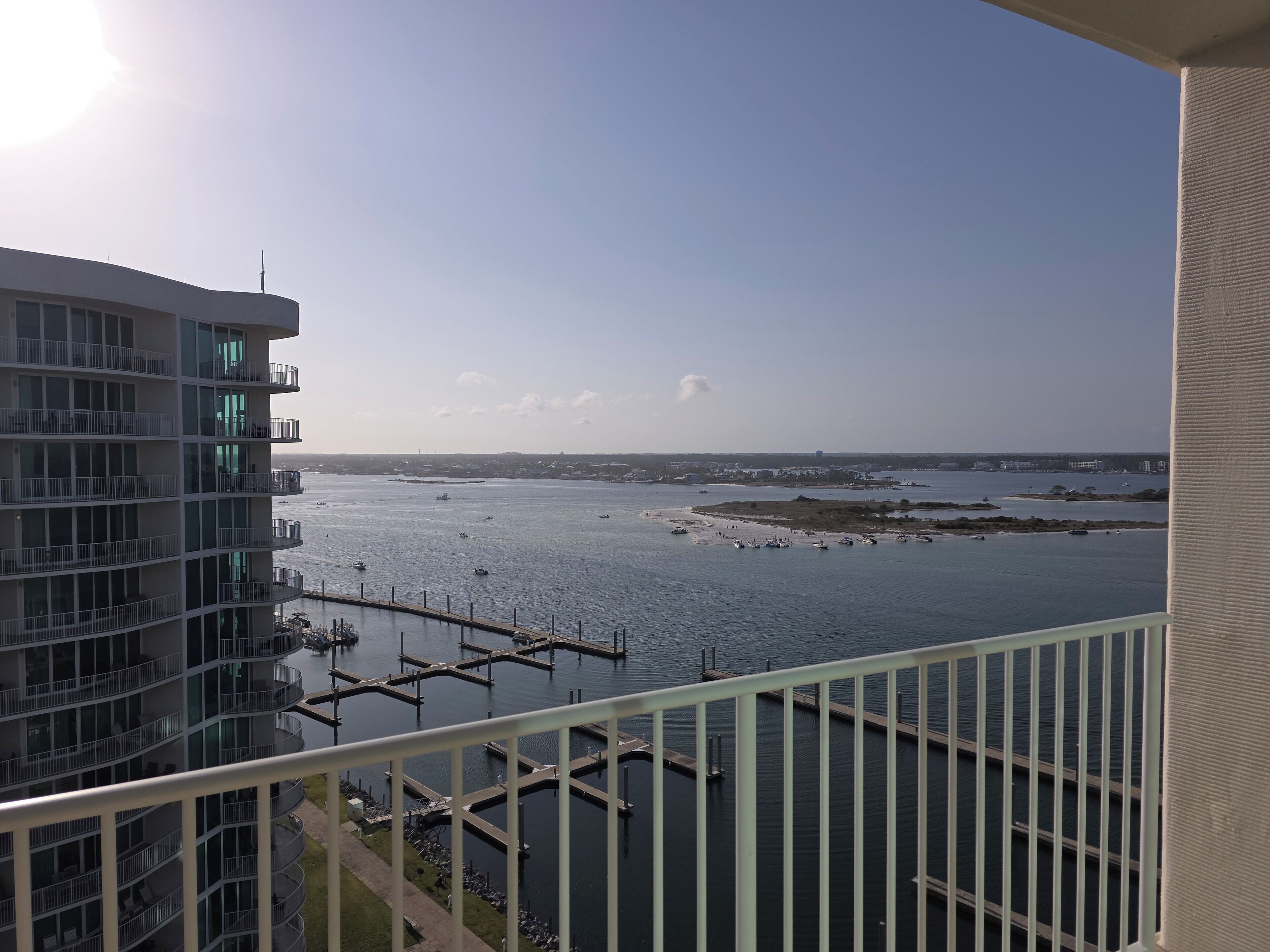 Ein Hochhaus mit zahlreichen Balkonen mit Blick auf eine Marina, in der Boote und Stege liegen.