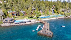 An aerial view of a coastal property with a dock, a swimming pool, and a tennis court. - Remodeled 4BR Lakefront w/ Exceptional Amenities (Kings Beach)