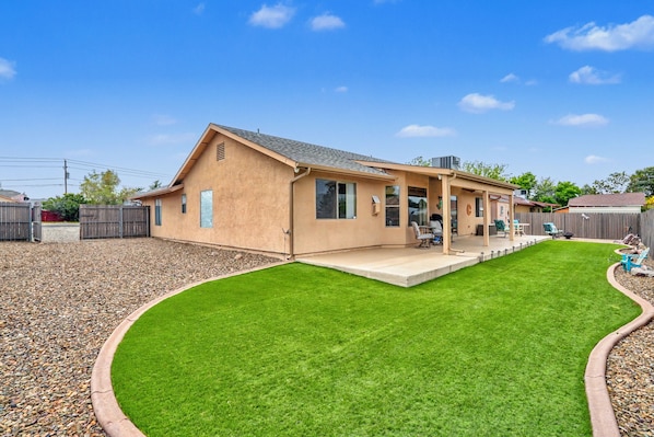 Une maison de plain-pied dotée d’un patio couvert, d’une pelouse bien entretenue et d’une clôture en bois.