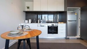 Une cuisine moderne avec des meubles blancs, des appareils en acier inoxydable et un coin repas comprenant une table et des chaises en bois.