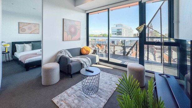 Un salon moderne avec un canapé, des poufs, une table basse et des œuvres d’art accrochées aux murs.