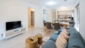Ein modernes Wohnzimmer mit Flachbildfernseher, einer Couch und einem Essbereich mit Stühlen und Tisch.