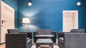 Una habitación con pared azul de acento, muebles de mimbre, una lámpara y una puerta con diseño de ladrillo.
