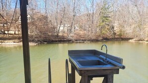 A wooden dock with a sink and a metal faucet, overlooking a calm body of water with trees in the background. - Catfish Cove at Watts bar Lake (Rockwood)