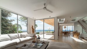 Un salon moderne doté d’une grande porte-fenêtre coulissante donnant sur un balcon avec vue sur l’océan.