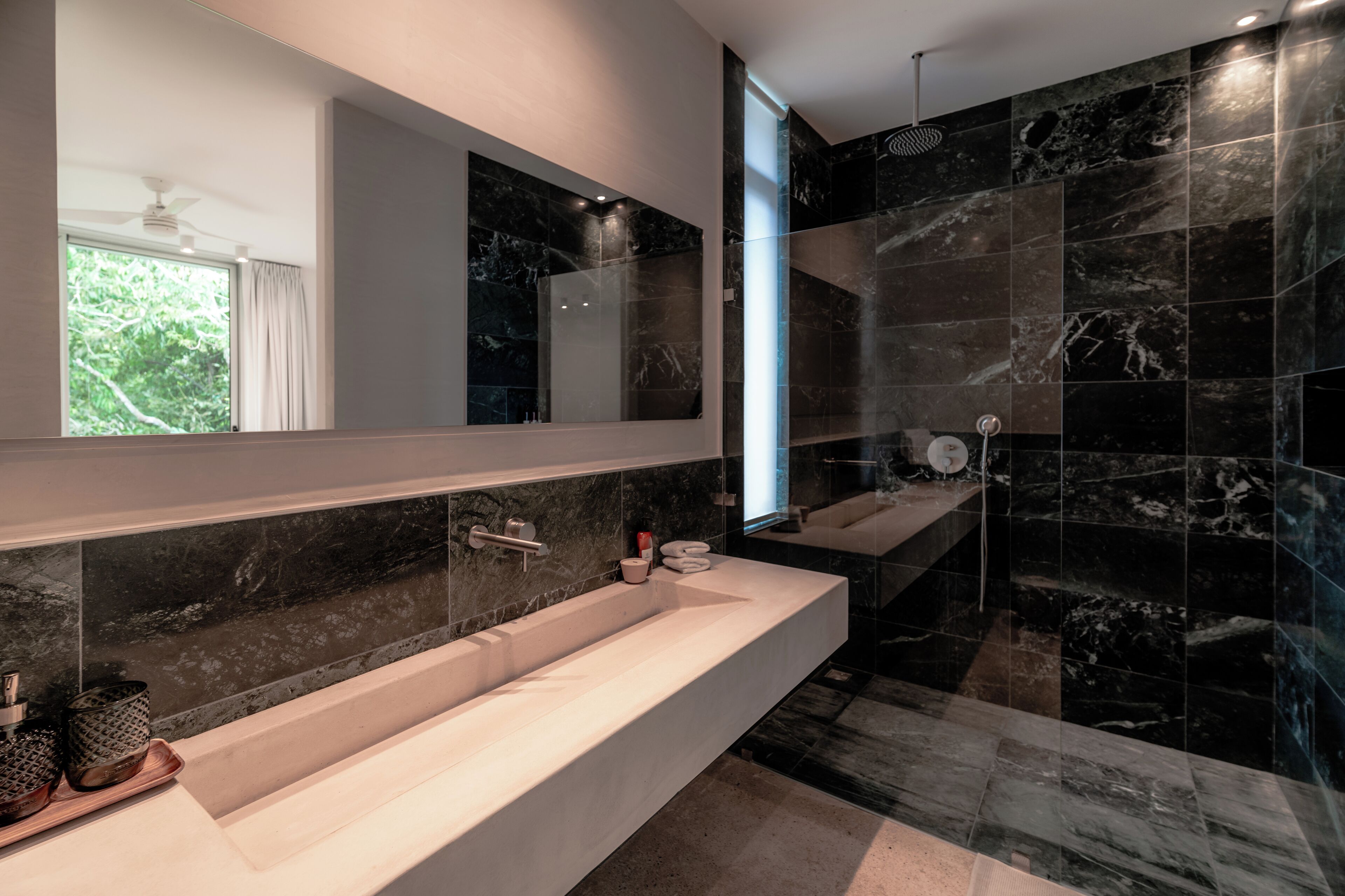 Un baño moderno con un espejo grande, un lavamanos amplio y una zona de ducha.