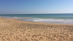 Ein Strand mit einer weiten Sandfläche und freiem Blick auf den Ozean.