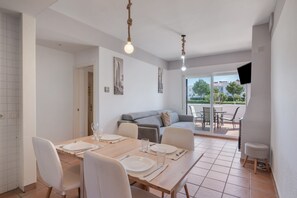 En matplats med ett bord för fyra personer, en soffa och en tv som är monterad på väggen.