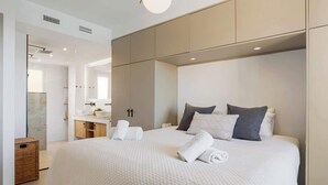 Ett modernt hotellrum med en stor säng, en inbyggd sminkbord och en stor spegel.