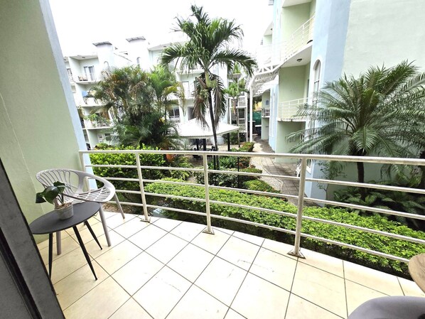 A balcony with a view of a residential area, including a pathway and greenery.