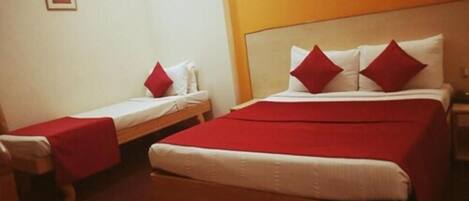 A hotel room with a large bed, two smaller beds, and red pillows.