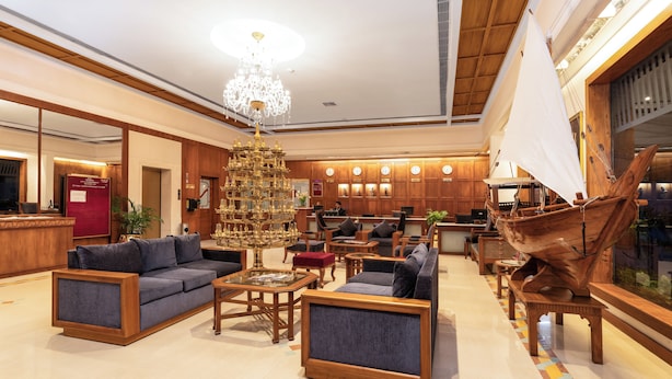 A spacious lobby with a grand chandelier, comfortable seating, a reception desk, and a large ship model.