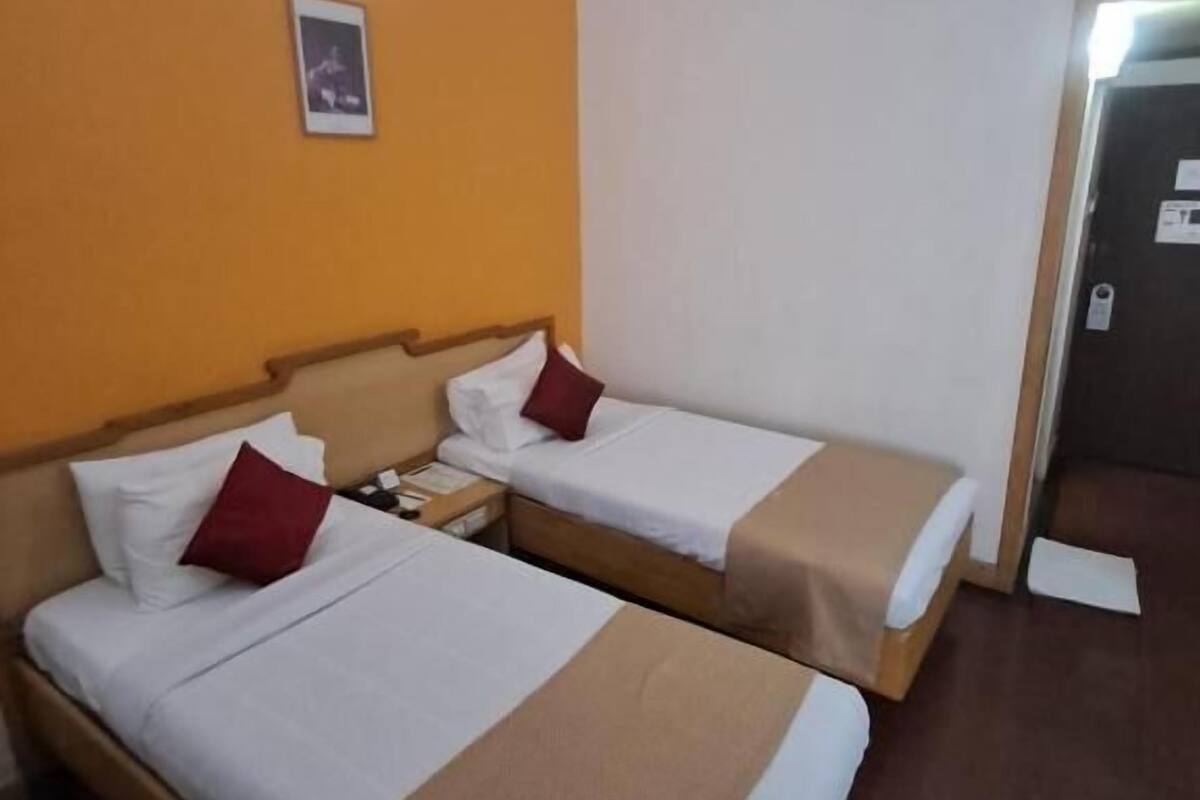 Ein Hotelzimmer mit zwei Betten, einem Nachttisch, einer Wandleuchte und einer Tür.