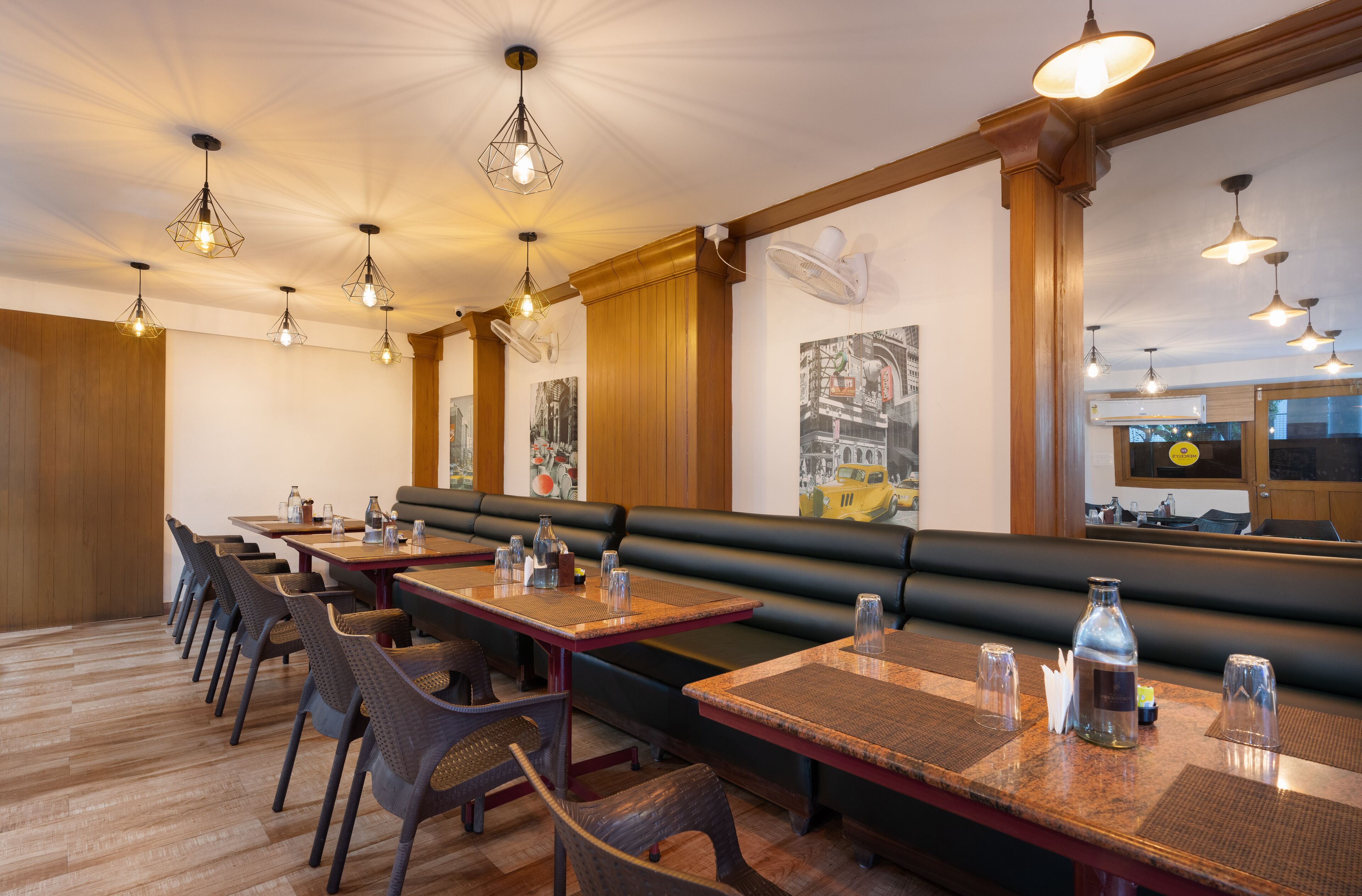 A restaurant with wooden flooring, black leather booths, and multiple tables with chairs.