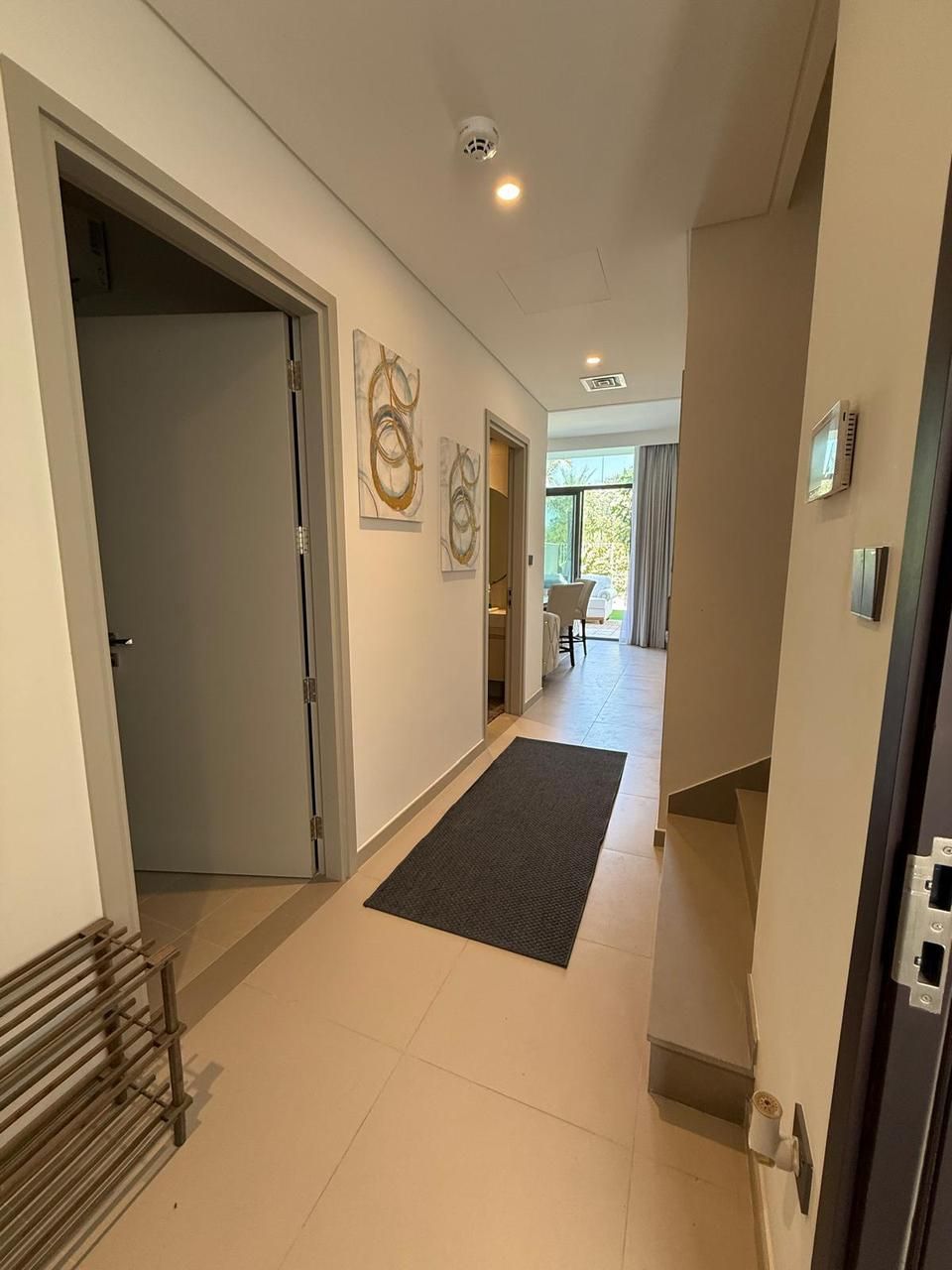 A modern hallway with a door, a mat, and a ceiling light.