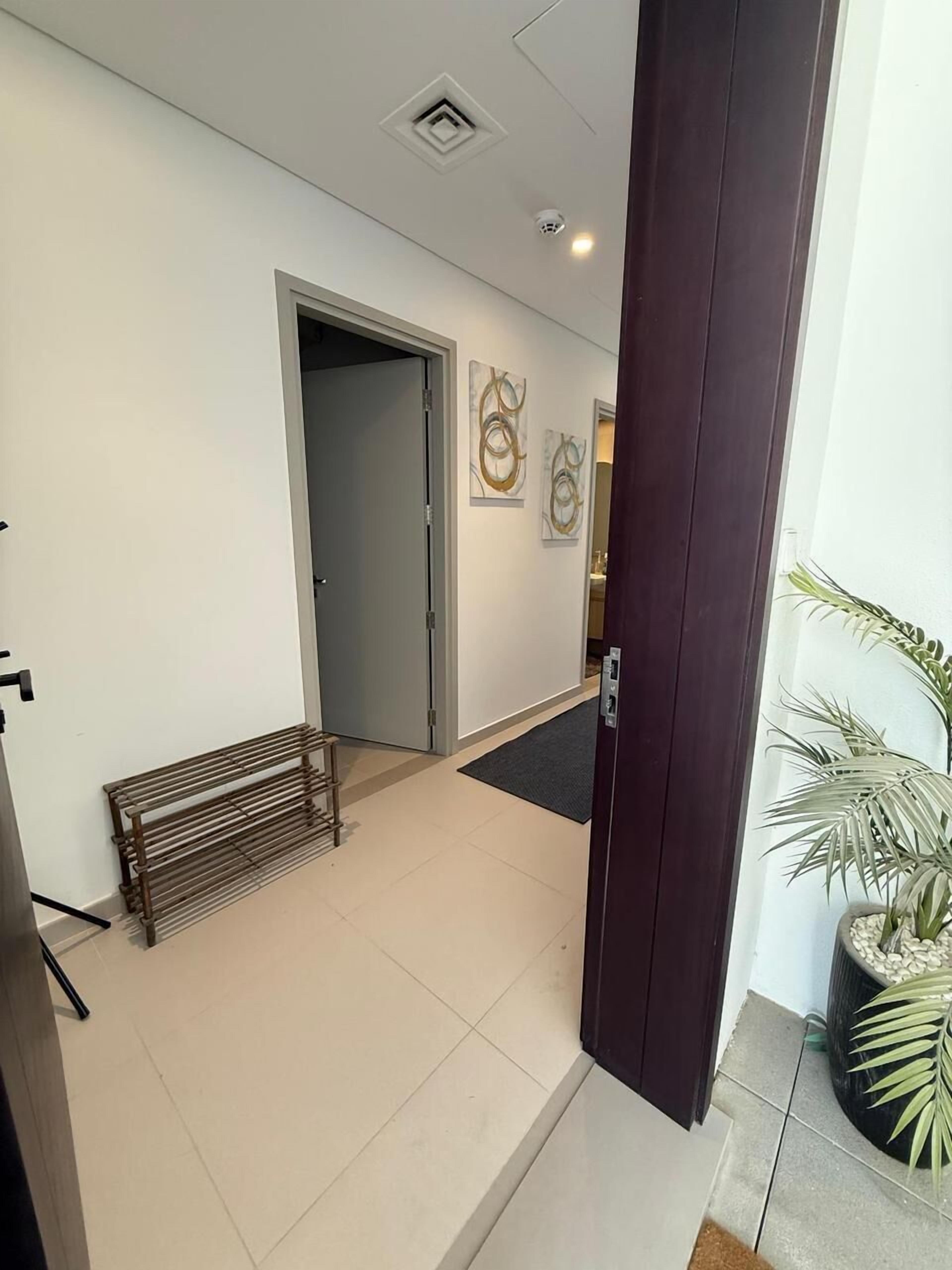 A modern hotel lobby with a bench, a door, and two abstract wall art pieces.