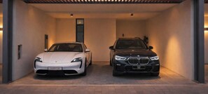 Two cars parked inside a building with a modern design, featuring a clean, minimalist interior and a visible door.