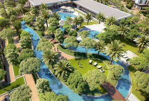 An aerial view of a resort with multiple swimming pools, palm trees, and lounge areas. - Elegant Stay in Ranches Villa (Dubai)
