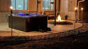 A hot tub in a covered outdoor area with a fire pit and candles. - Hot Tub, Fire Pit, Near the Beach! (Edgewater)