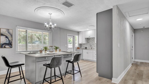 A modern kitchen with a central island, bar stools, and a chandelier. - Hot Tub, Fire Pit, Near the Beach! (Edgewater)