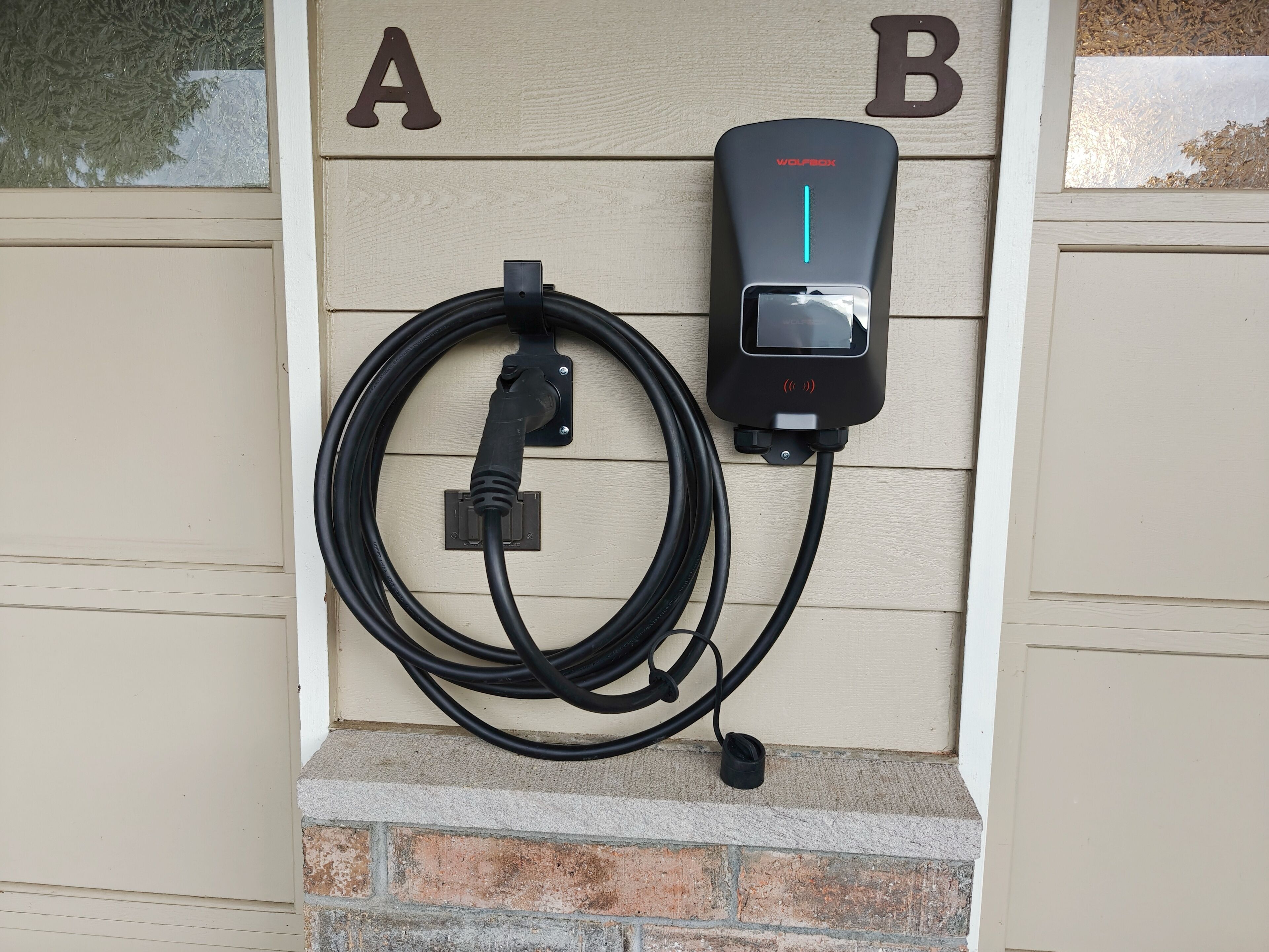 Eine an der Wand montierte Ladestation für Elektroautos, mit angeschlossenem Kabel.