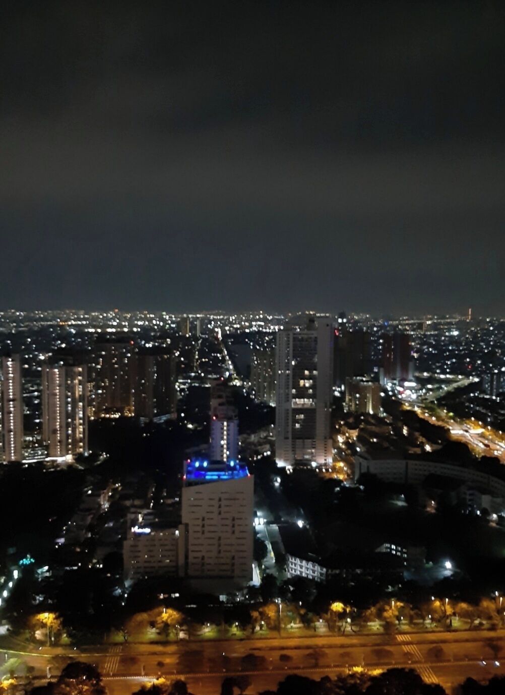 A nighttime cityscape with high-rise buildings and illuminated streets.