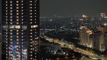 A high-rise building with multiple floors, likely a hotel, with illuminated windows suggesting interior lighting. The surrounding area is urban with visible roads and other buildings, indicating a cityscape.
