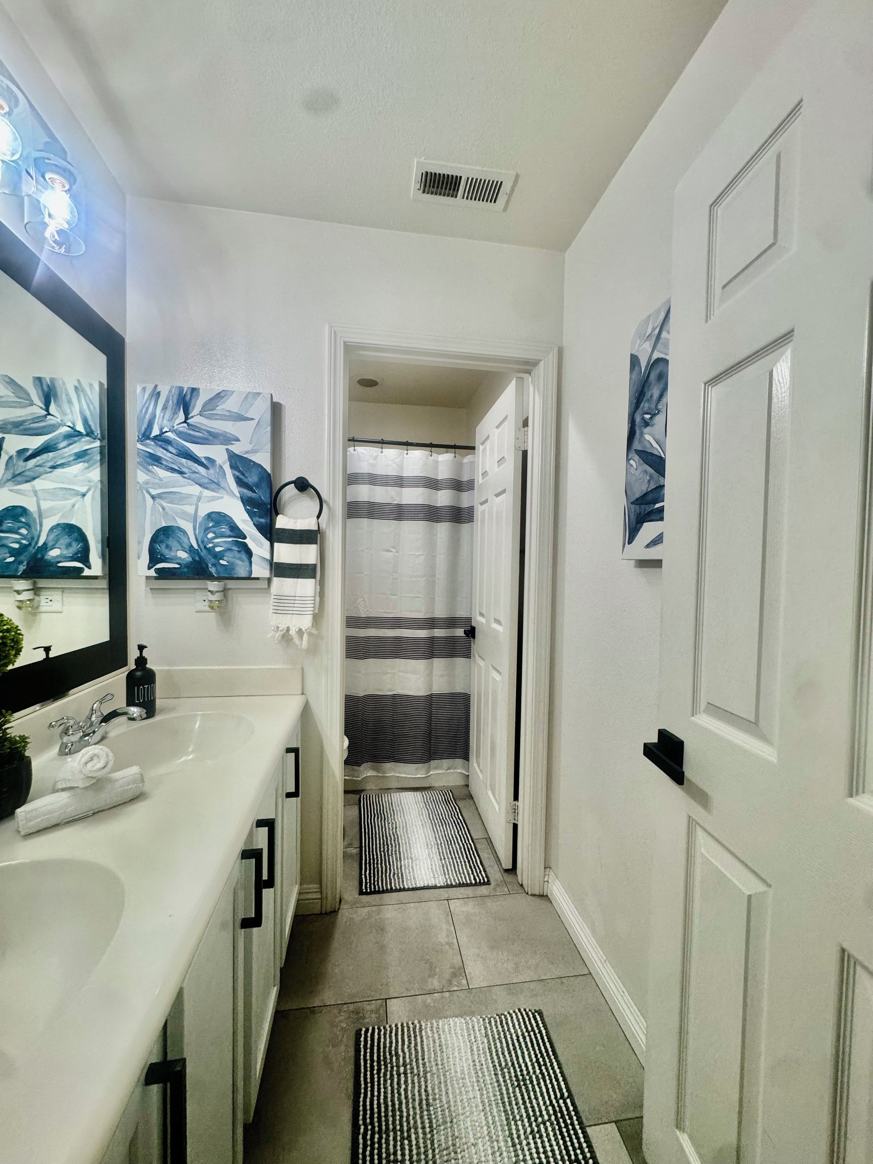 Une petite salle de bain avec un lavabo blanc, un miroir et un rideau de douche.