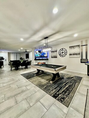 Relax in this stylish living room with a pool table, flat-screen TV, and cozy fireplace.