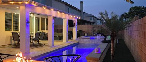 Una casa moderna con piscina, mobiliario exterior e iluminación con guirnaldas.