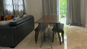 Ein modernes Wohnzimmer mit einem schwarzen Sofa, einem Esstisch und einem transparenten Glasstuhl.