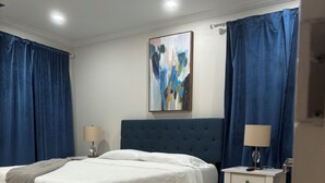Ein Schlafzimmer mit einem Bett, einem Nachttisch, einer Lampe und einem Bild an der Wand.