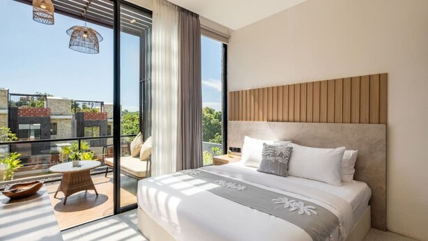 A modern bedroom with a large bed, a balcony with a view, and a dining area.