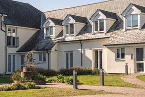 A row of residential buildings with pitched roofs and multiple windows. - Stylish Apartment, Garden with Beautiful Sea Views (Newquay)