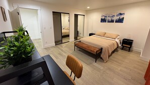 Une chambre à coucher comprenant un lit, des tables de chevet, un bureau, une chaise, un miroir et une plante en pot.