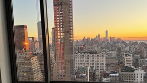 Une vue depuis une fenêtre donnant sur un paysage urbain, avec un bâtiment en construction bien visible et un ciel dégagé.