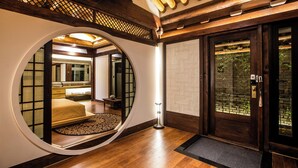 A traditional Japanese room with tatami flooring, a round window, and a sliding door leading to a garden. - Ohsudang Hanok Stay (Gyeongju)