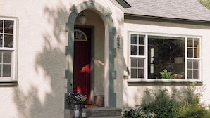 A house with a red door, white exterior, and a brick chimney.