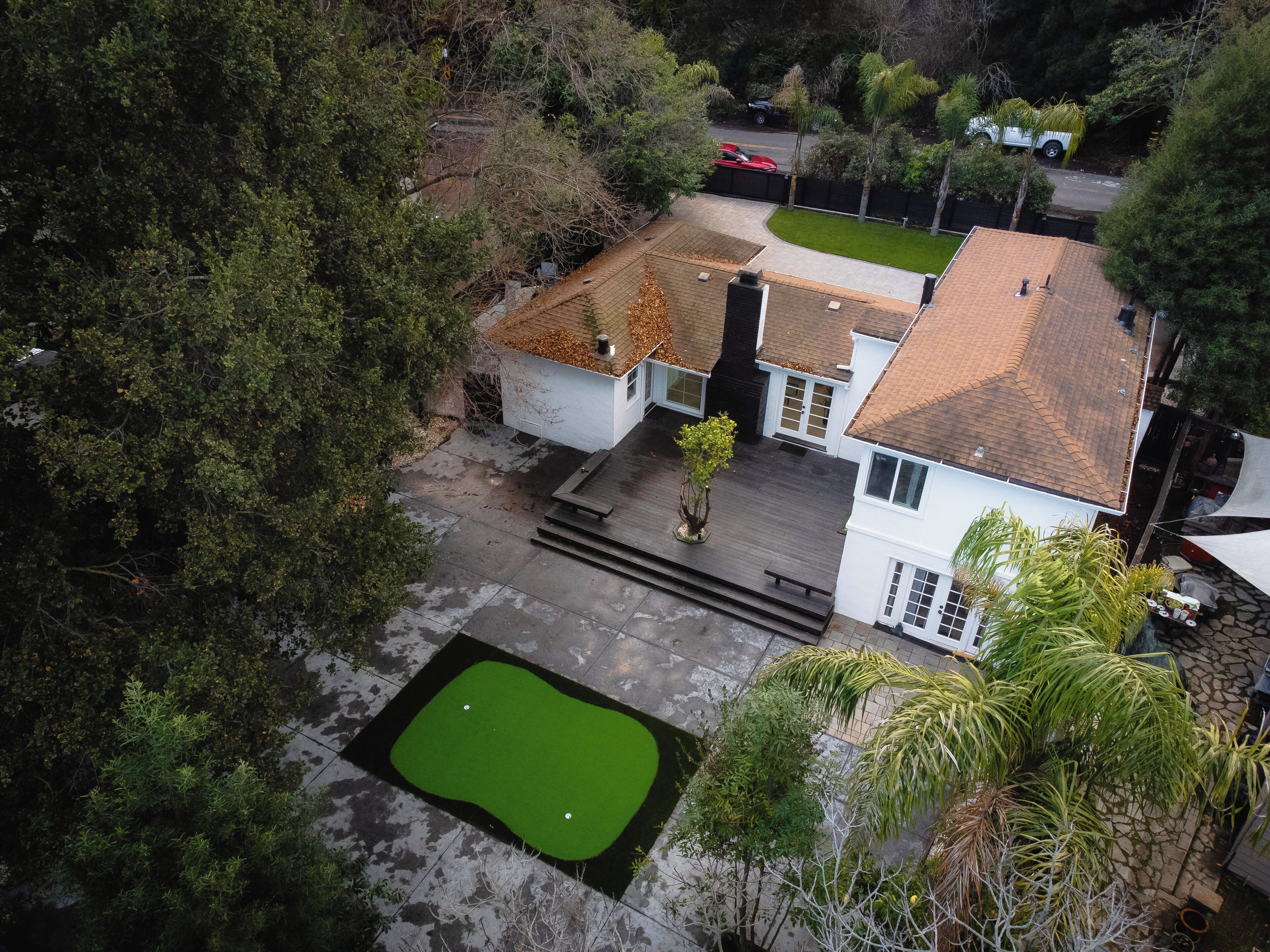 Propiedad residencial con césped verde, un pequeño patio y una entrada para vehículos.